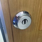 Escudo protector de acero instalado en puerta de madera como parte de soluciones y seguridad en cerrajería
